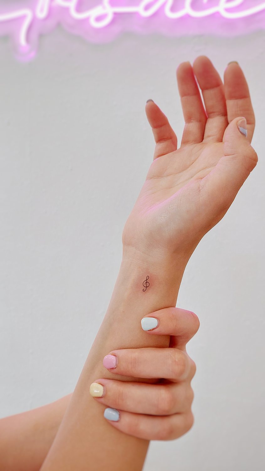 Tatuaje de clave de sol en muñeca hecho con técnica de línea fina en un estudio de Valencia