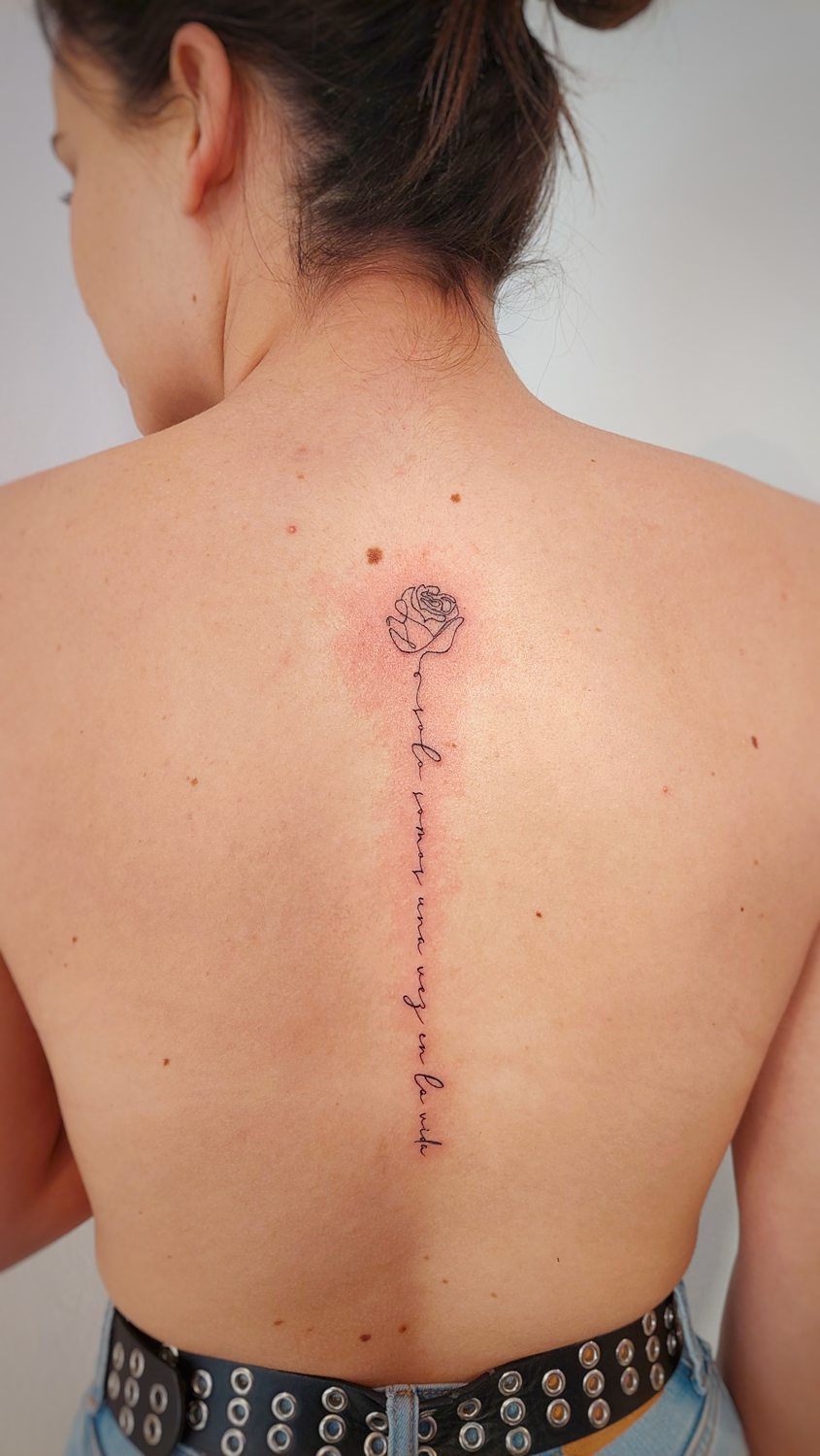 Tatuaje de rosa y frase en la espalda
