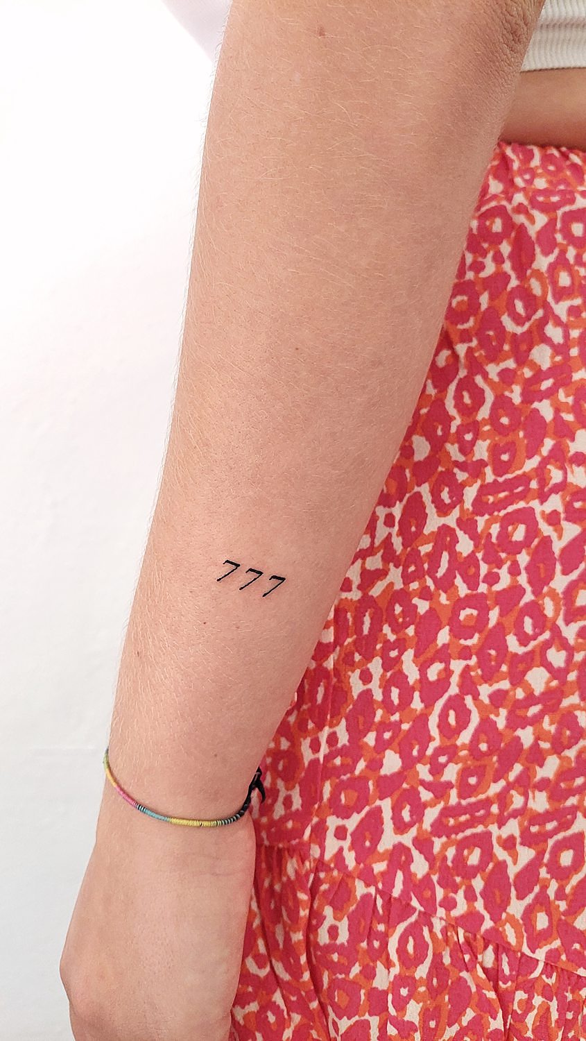 Tatuaje de número 777 en el antebrazo
