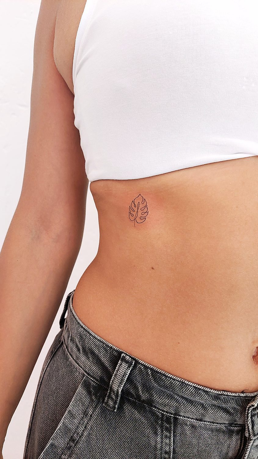 Tatuaje pequeño de hoja cerca de las costillas hecho con técnica de línea fina en Grisáceos Ink