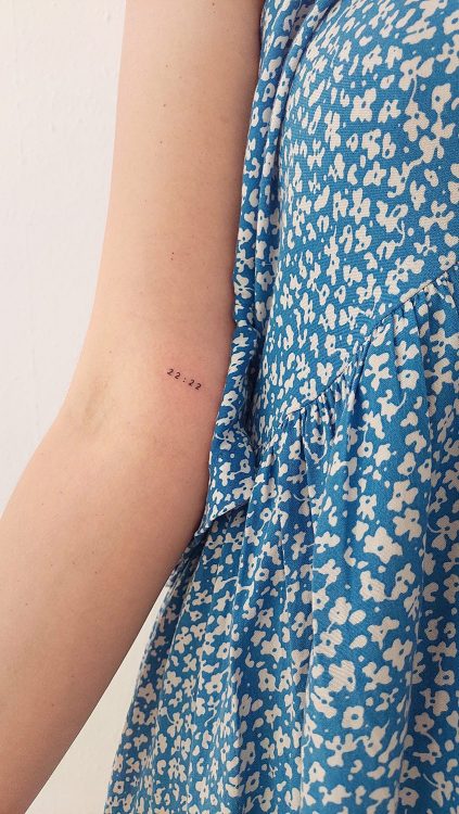 Tatuaje de la hora 22:22 en brazo con vestido azul.
