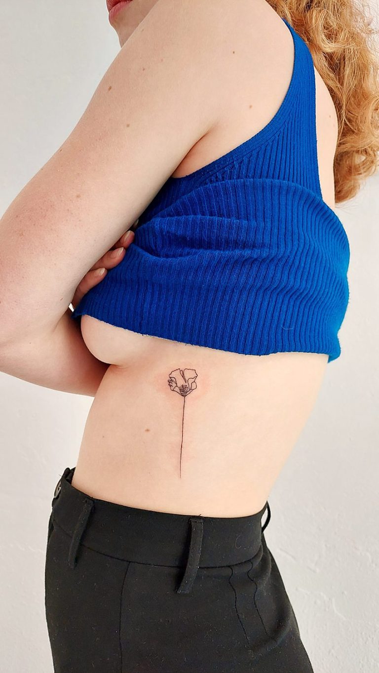 Tatuaje de flor en el costado en una mujer hecho con técnica de línea fina