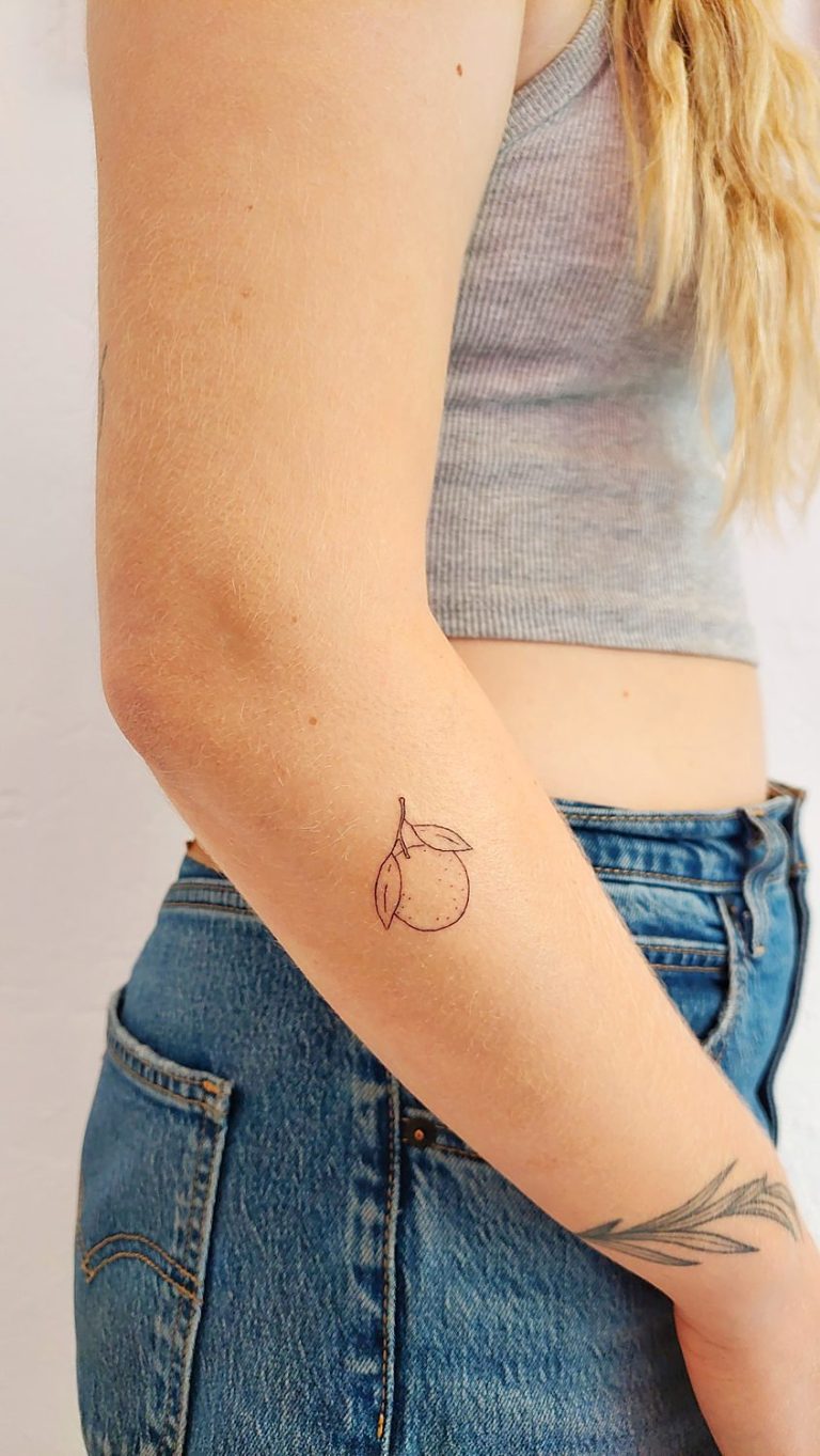 Tatuaje de naranja en el brazo hecho con técnica de línea fina en un estudio de Valencia