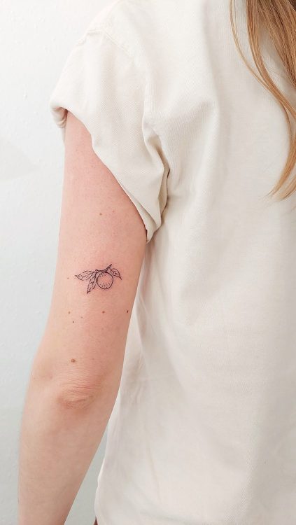 Tatuaje de naranja con rama en el brazo