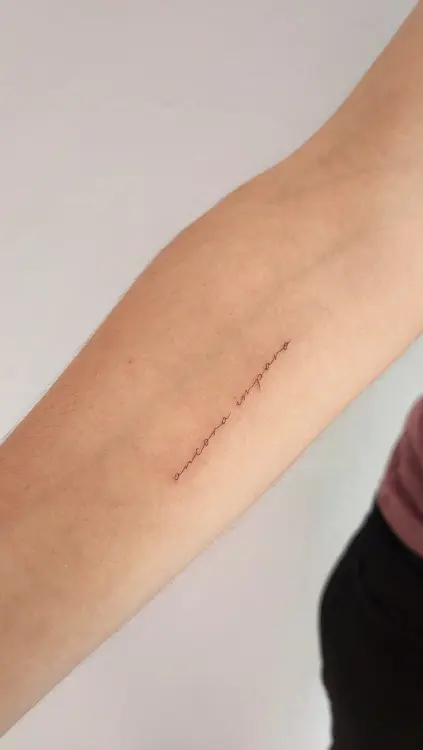 Tatuaje brazo con texto 'ancora imparo' elegante.