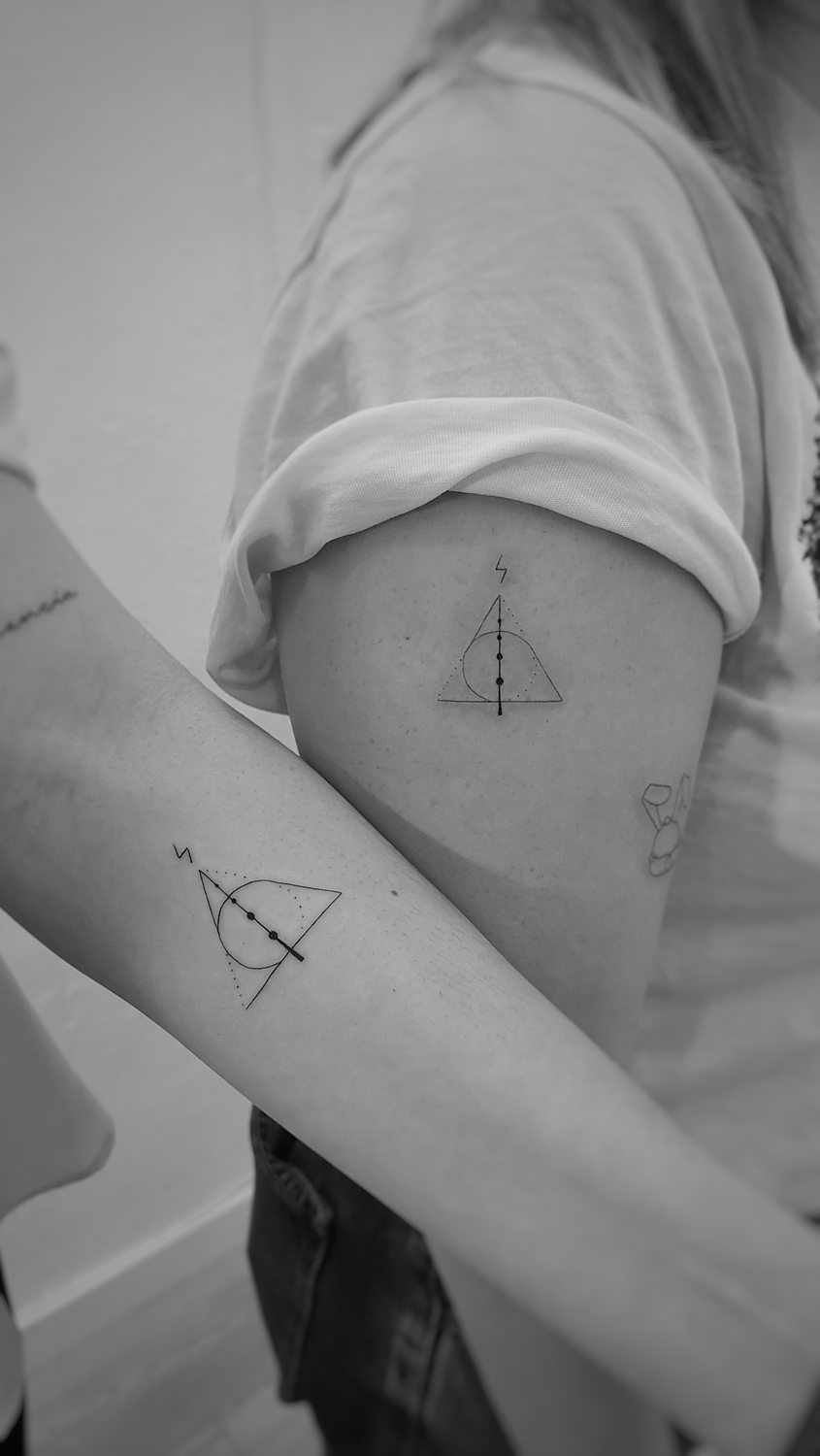 Tatuajes geométricos idénticos en brazos de dos personas.