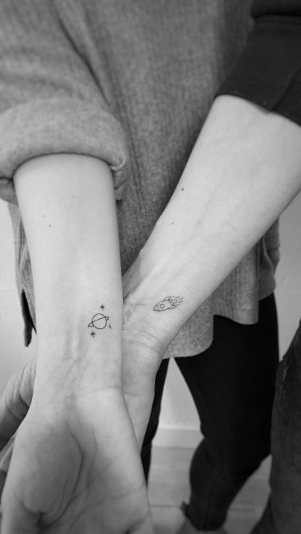 Tatuajes de cohete y planeta en brazos