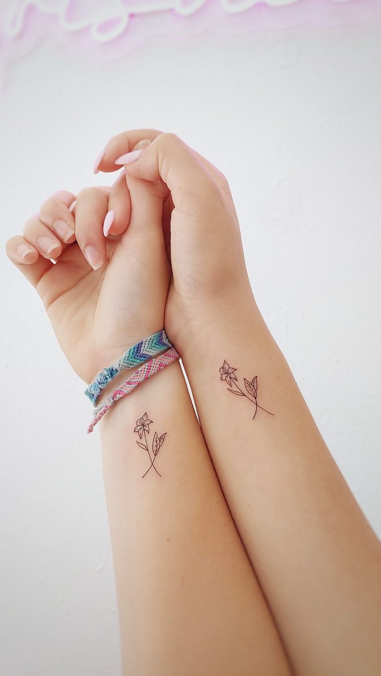 Tatuajes de flores en muñecas con pulsera tejida.