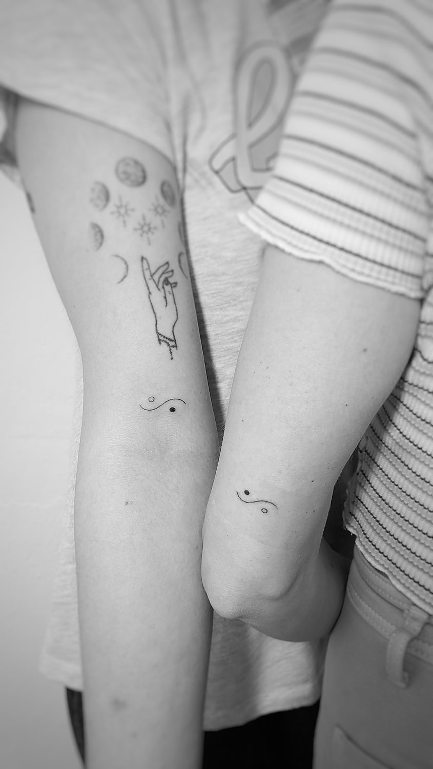 Dos brazos con tatuajes minimalistas en pareja del ying y el yang