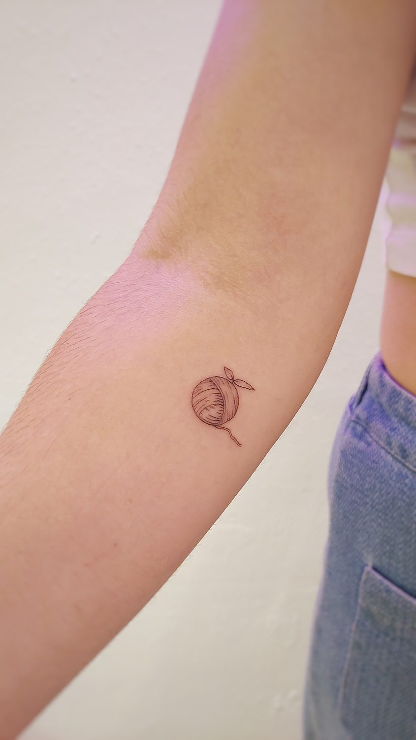 Tatuaje de ovillo de lana en el brazo