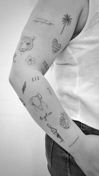 Brazo con varios tatuajes pequeños en blanco y negro.