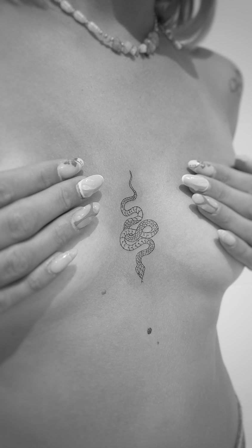 Tatuaje de serpiente en el pecho hecho con técnica de línea fina en el estudio de tatuajes Grisáceos Ink (Valencia)