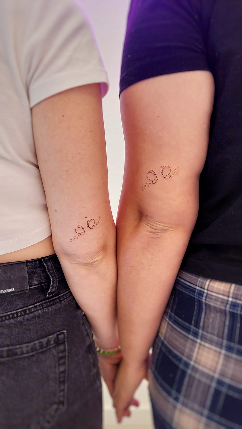 Dos personas con tatuajes de mariposas en el brazo.