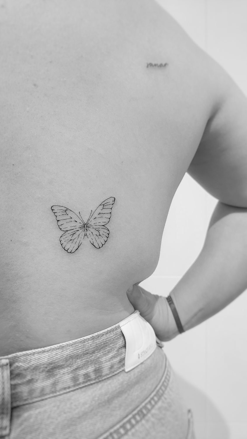 Tatuaje de mariposa en la espalda de mujer.