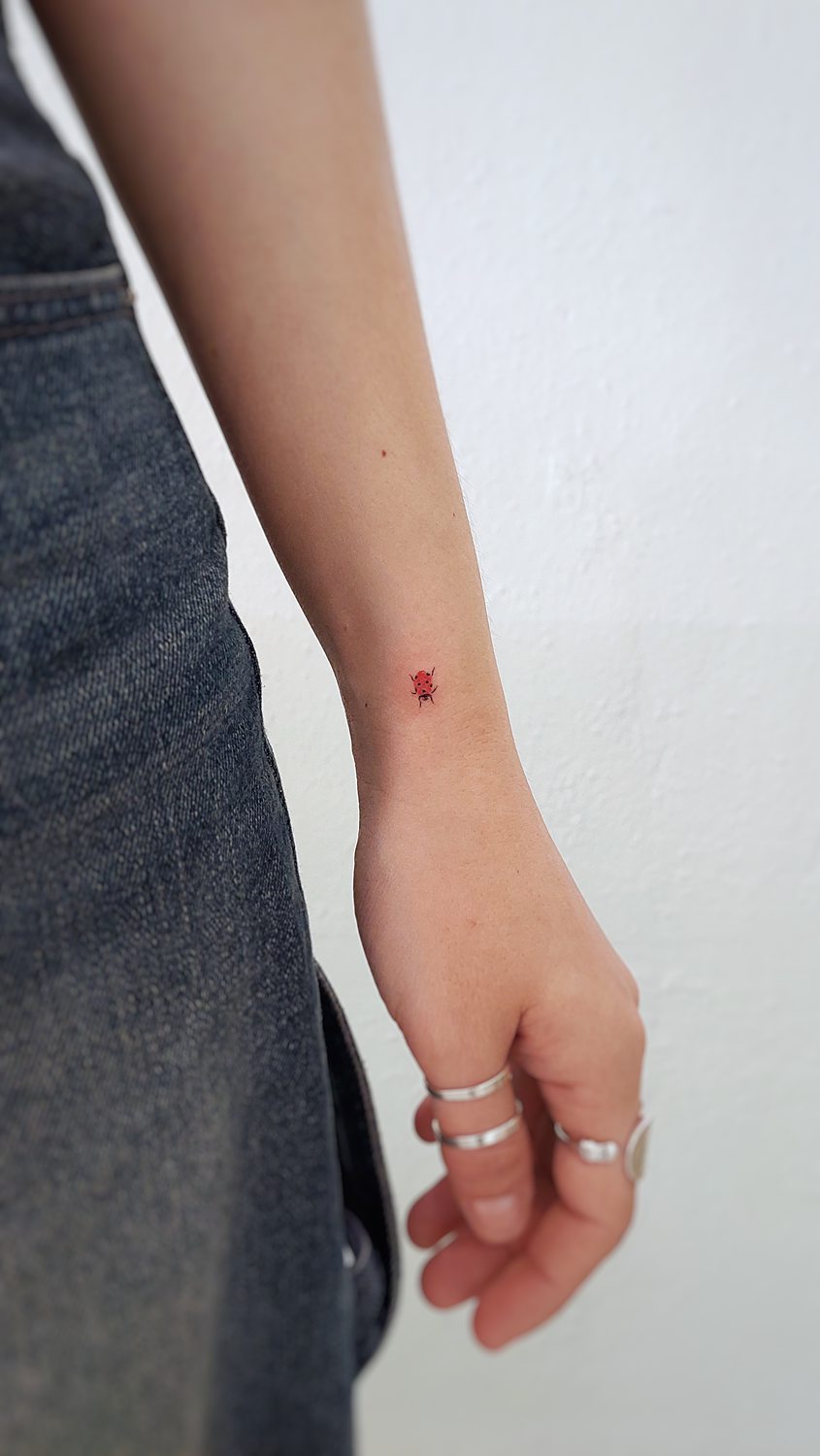 Tatuaje mini de mariquita en la muñeca