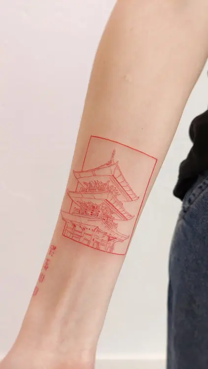 Tatuaje rojo de templo japonés en el brazo hecho con técnica de línea fina en Grisáceos Ink, estudio de tatuajes en Valencia