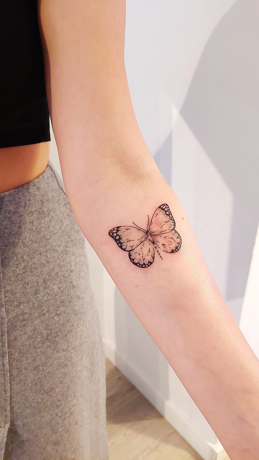 Butterfly tattoo on arm, minimalist design