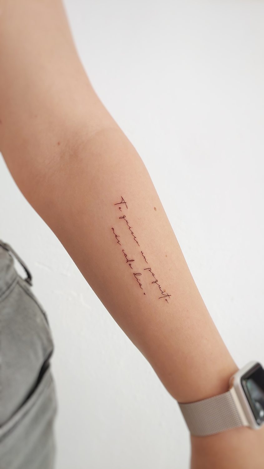 Tatuaje en brazo con cita cursiva en la que se lee "Te quiero un poquito más cada día" hecho en un estudio especializado en línea fina de Valencia