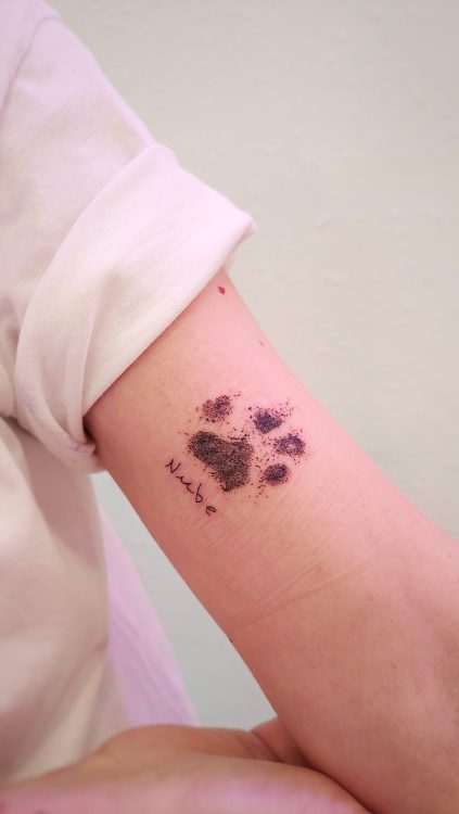 Tatuaje de huella de perro en el brazo.