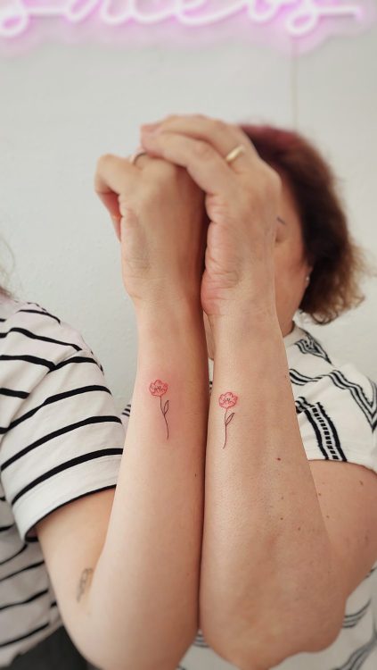 Tatuajes de flores en brazos de dos personas.