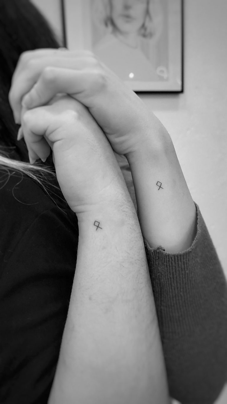 Manos unidas con pequeños tatuajes en las muñecas.