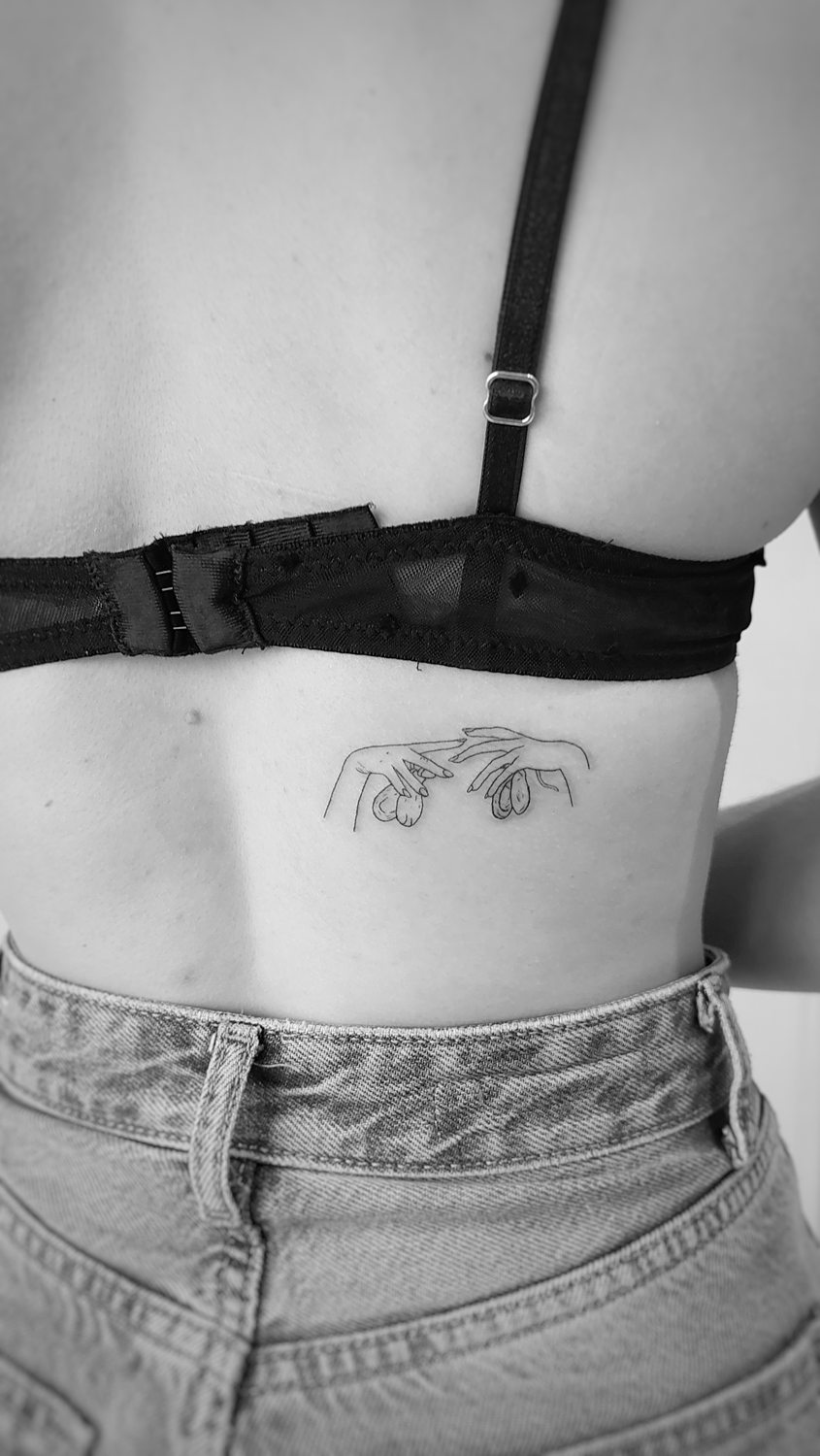 Tatuaje de manos en la espalda baja.