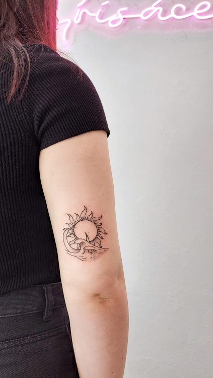 Tatuaje minimalista de sol y luna en brazo.