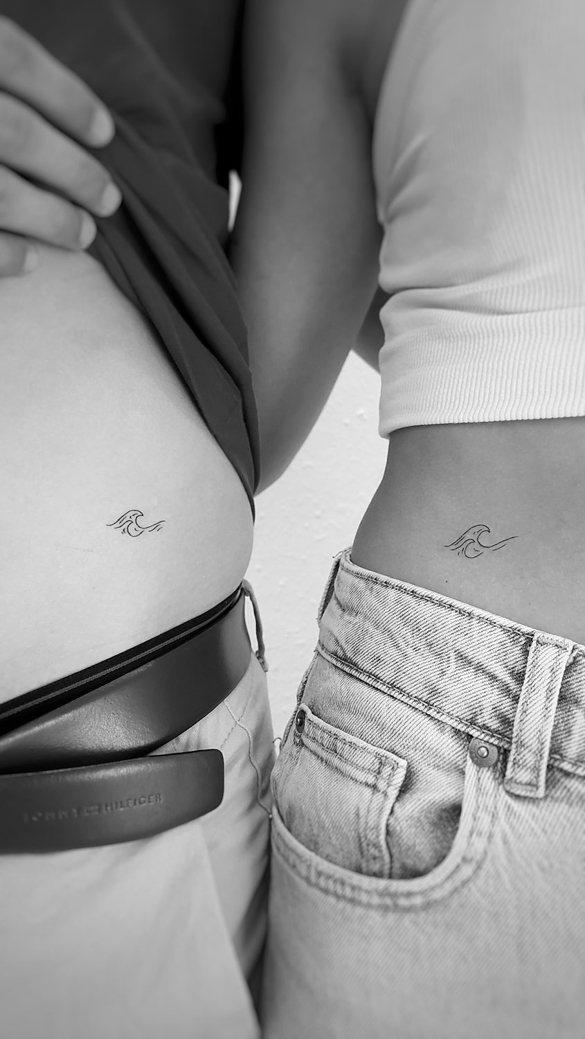 Pareja mostrando tatuajes iguales en la cintura.