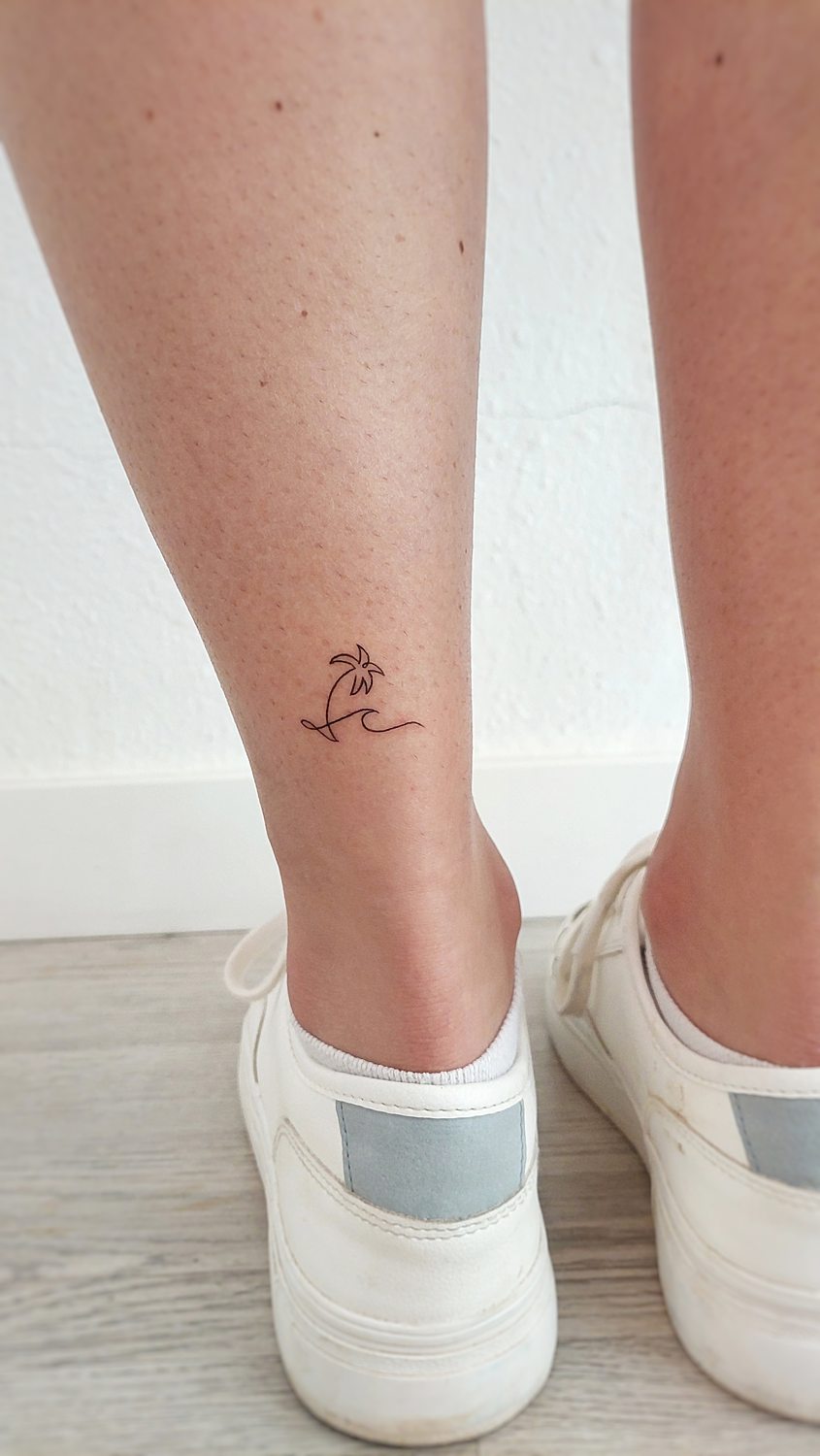 Tatuaje minimalista de palmera en la pierna