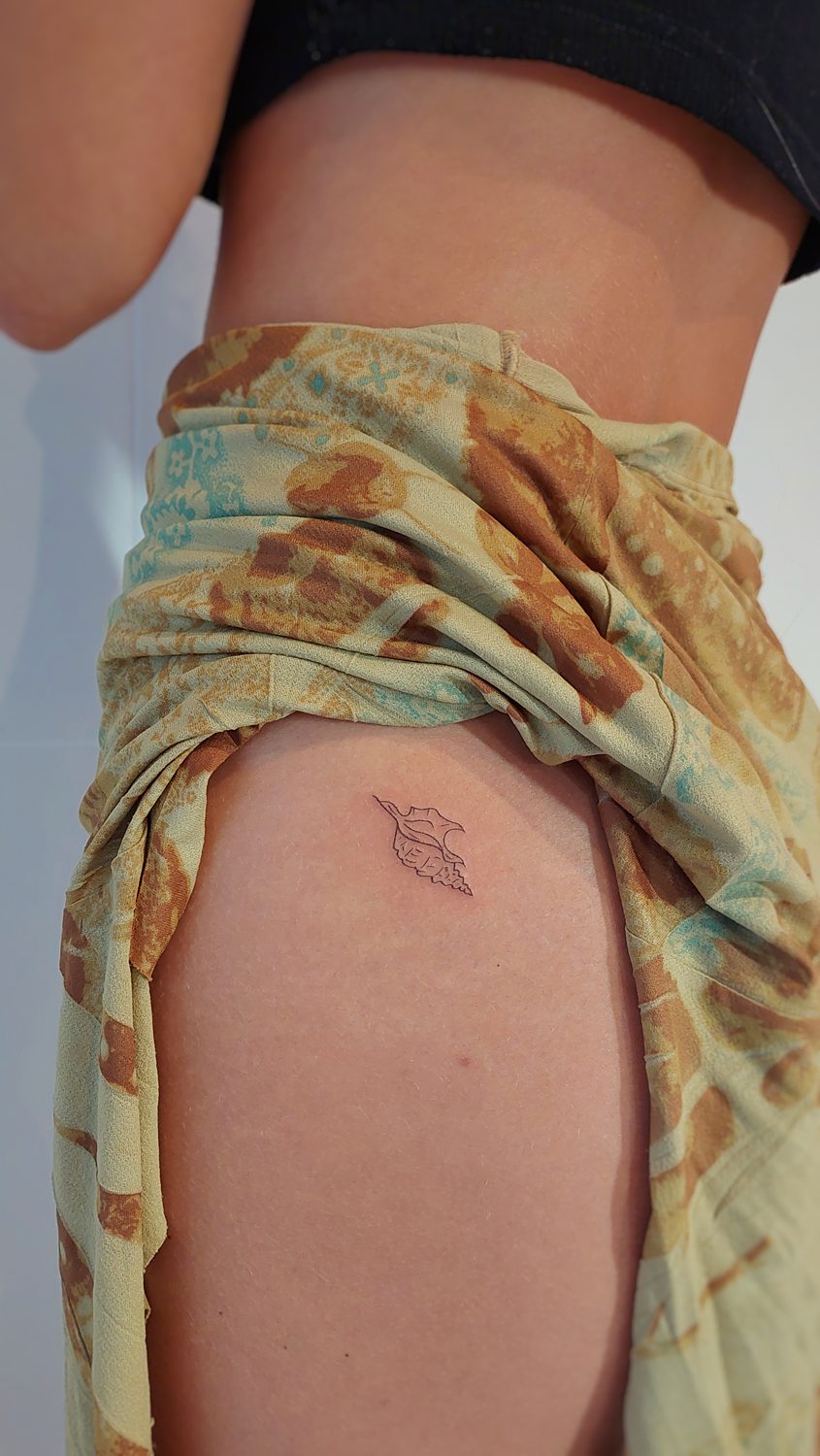Tatuaje minimalista de concha en la cadera