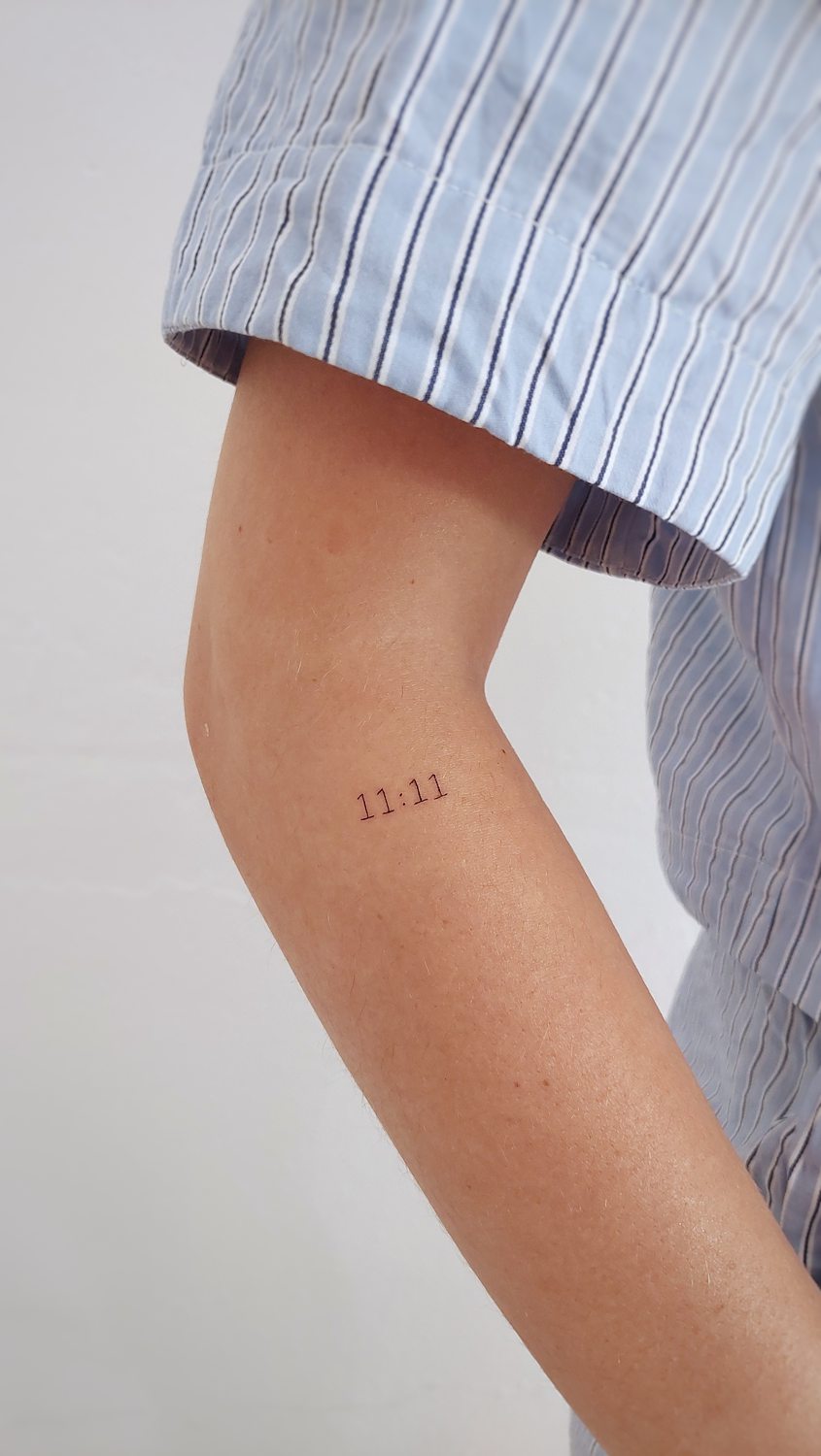Tatuaje del número 11:11 en el brazo de una mujer