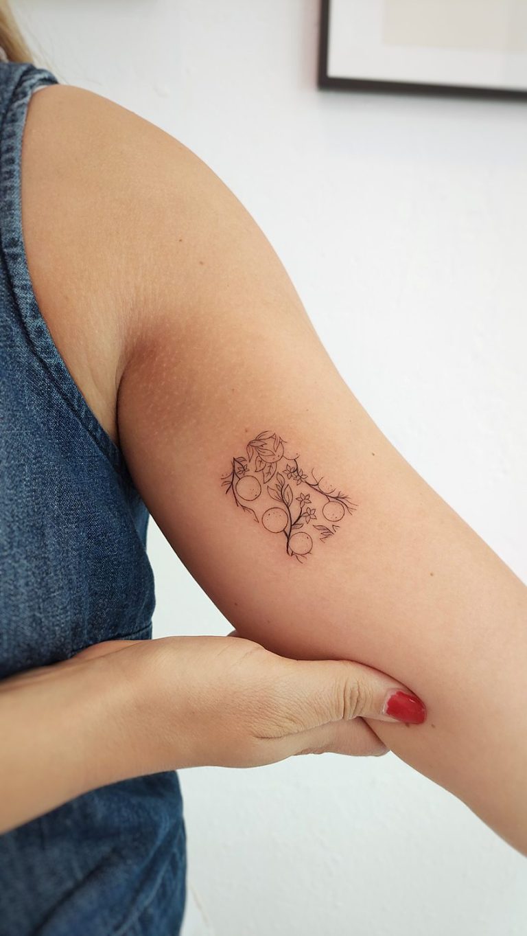 Tatuaje mosaico de naranjas con azahar en el interior del brazo de una mujer
