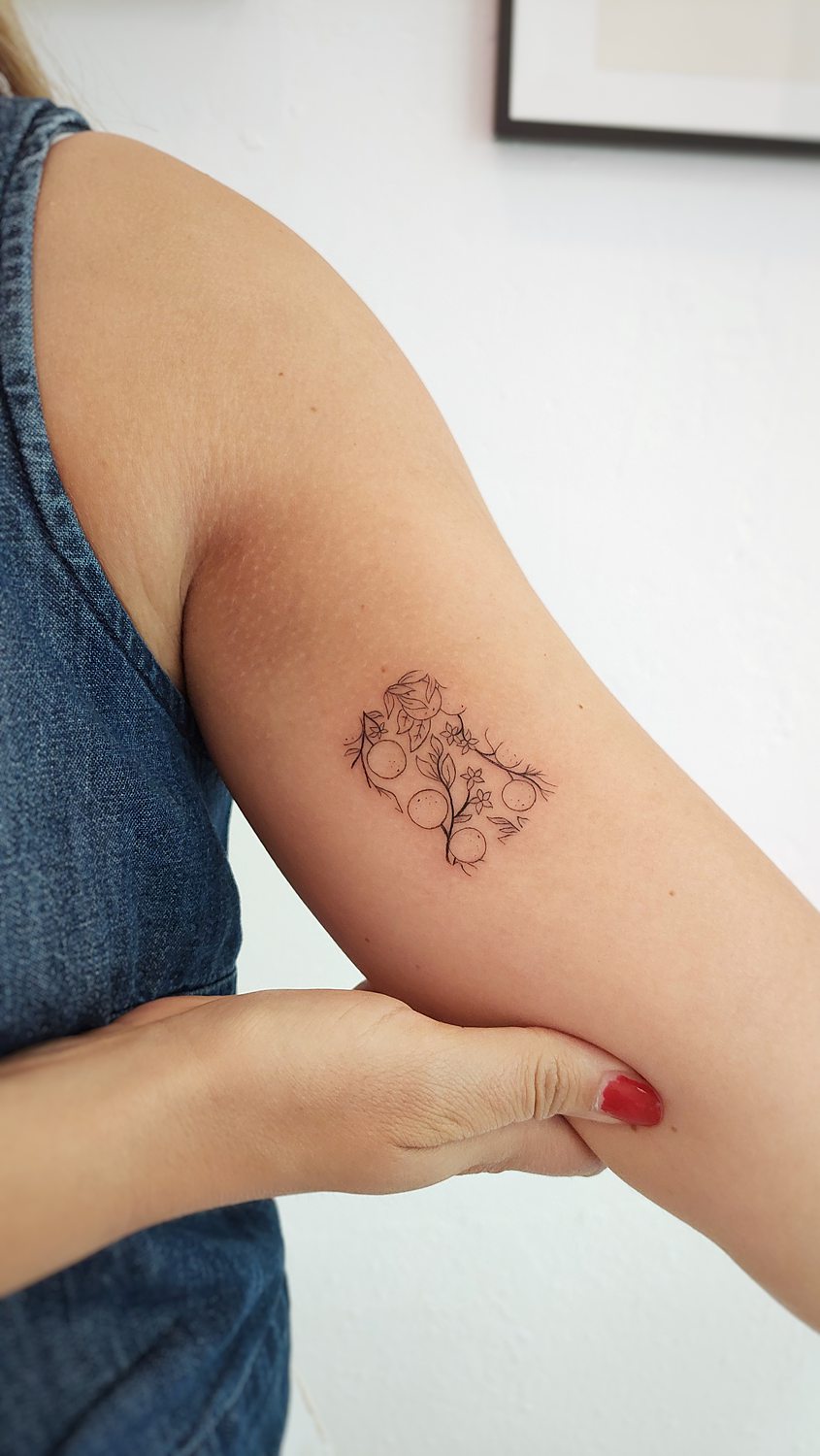 Tatuaje mosaico de naranjas con azahar en el interior del brazo de una mujer