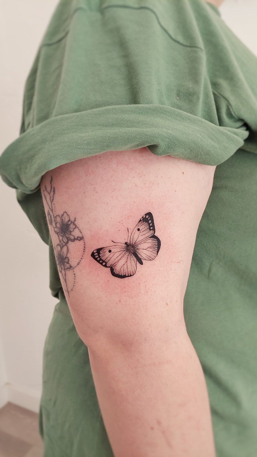 Tatuaje de mariposa negra detallada en el brazo.