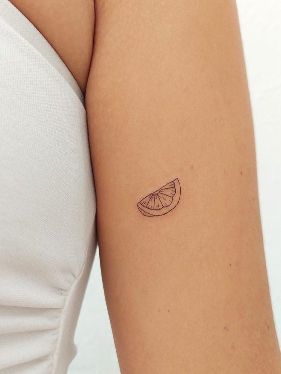 Tatuaje de una rodaja de limón en la parte superior del brazo.