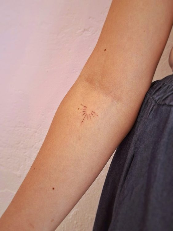 Tatuaje minimalista de diente de león en un brazo.